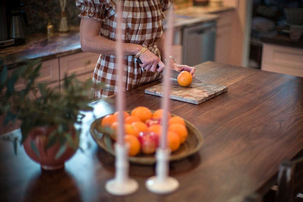 Woman cutting oranges on a cutting board on a kitchen island with a butcher block countertop