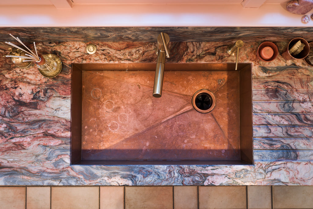 Copper sink with pink and blue-veined quartzite countertops