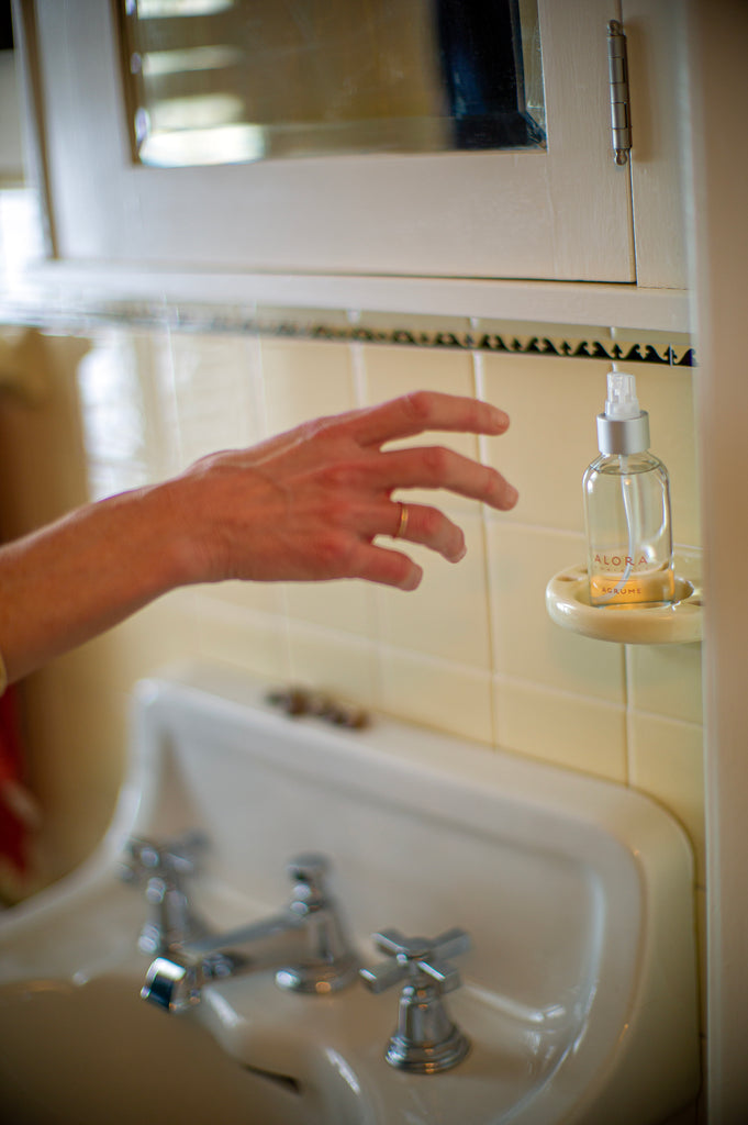 Woman reaching for room spray bottle in bathroom