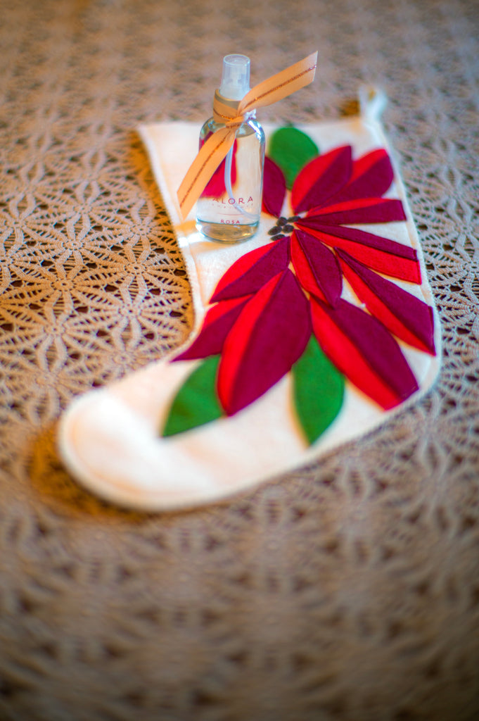 Alora room spray bottle wrapped with a pink bow sitting on top of a Christmas stocking