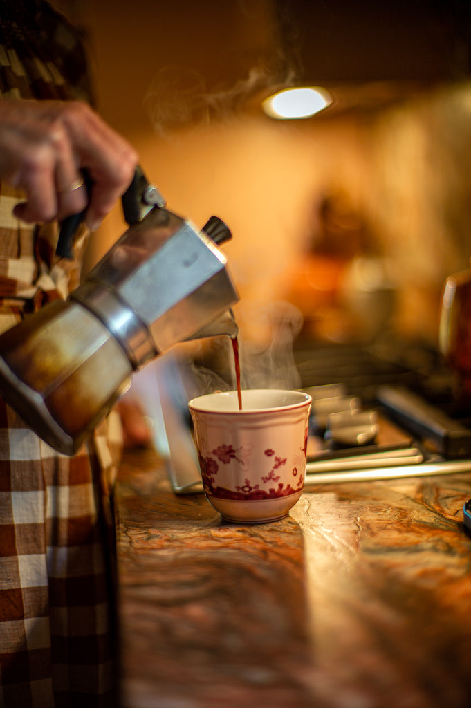 Woman pouring cup of coffee from Bialetti coffee maker