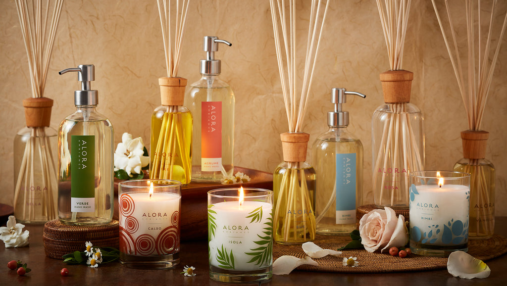 A variety of reed diffusers, candles, and hand washes spread amongst each other against a brown backdrop