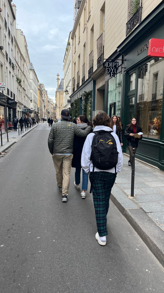 Man with arm around daughter walking streets of Paris while son walks behind