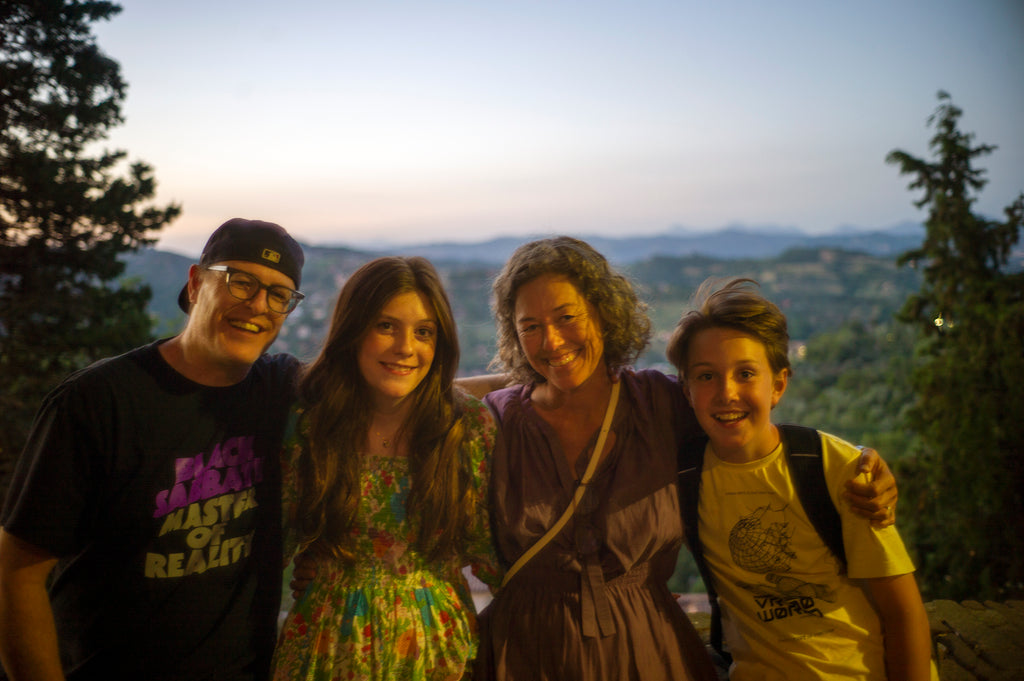 Dad, girl, boy, and mom in front of hills of Italian countryside