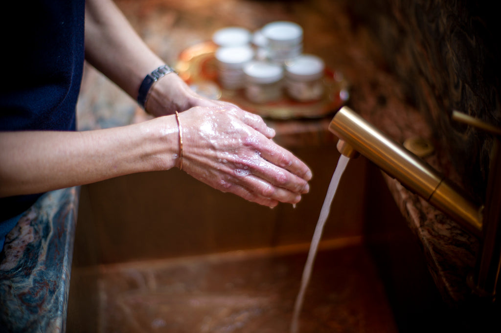 Woman washing hands in a kitchen sink.