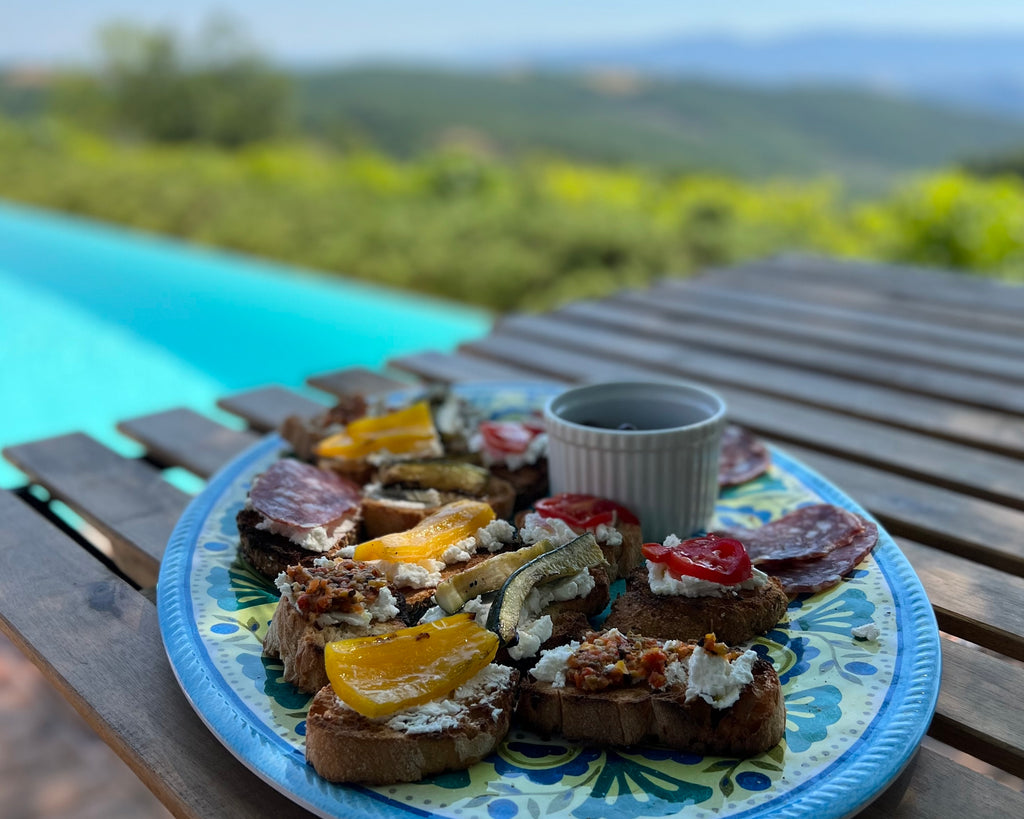 Plate of veggie-topped crostini next to a pool