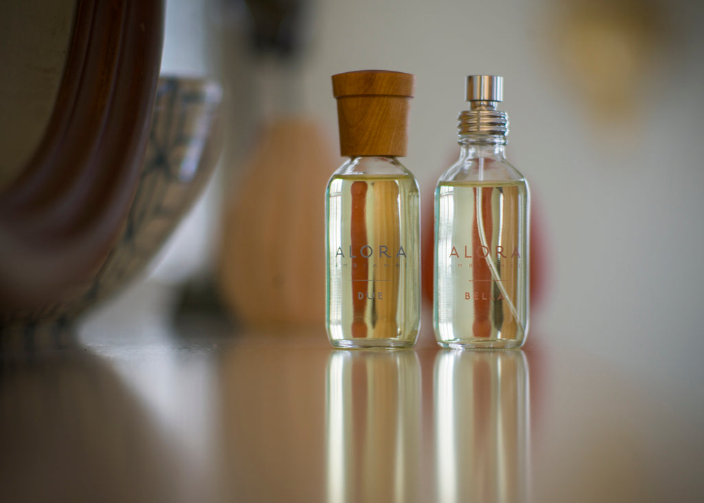 Two small fragrance bottles with wood caps. Bottles are labeled Due and Bella.