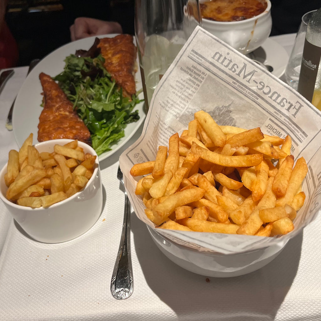 French fries and breaded chicken plated on a bead of greens