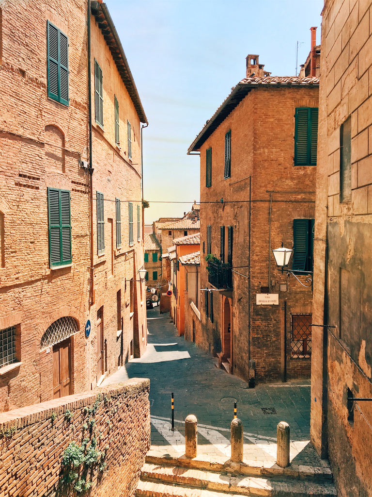 Winding Italian city streets with large old buildings towering on each side of the street