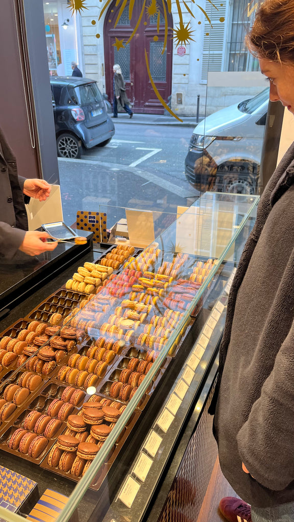 Girl looking at an array of macarons in a display case