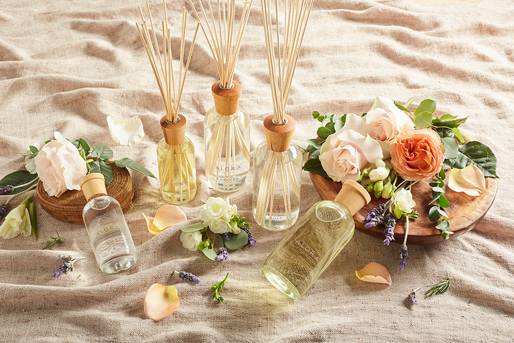 Reed diffusers surrounded by various types of flowers