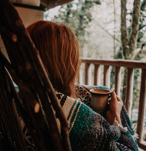 woman covered with blanket drinking marshmallow tea on back porch