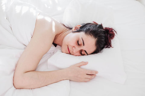 Young woman in bed using a natural latex pillow from Rest Organic