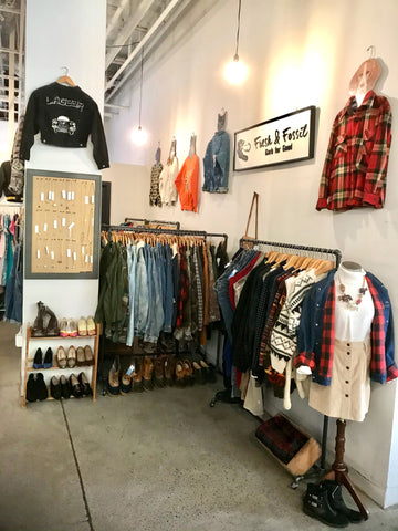 Racks on clothing are pictured next to a wall. There is a dressed mannequin at the front.