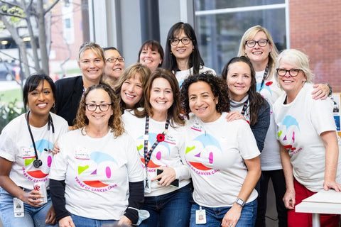 A group of Cancer Centre staff wearing their Cancer 20th anniversary t-shirts pose for a photo