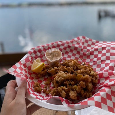 fried whole belly clams and tartar sauce on a basket lined with wax paper