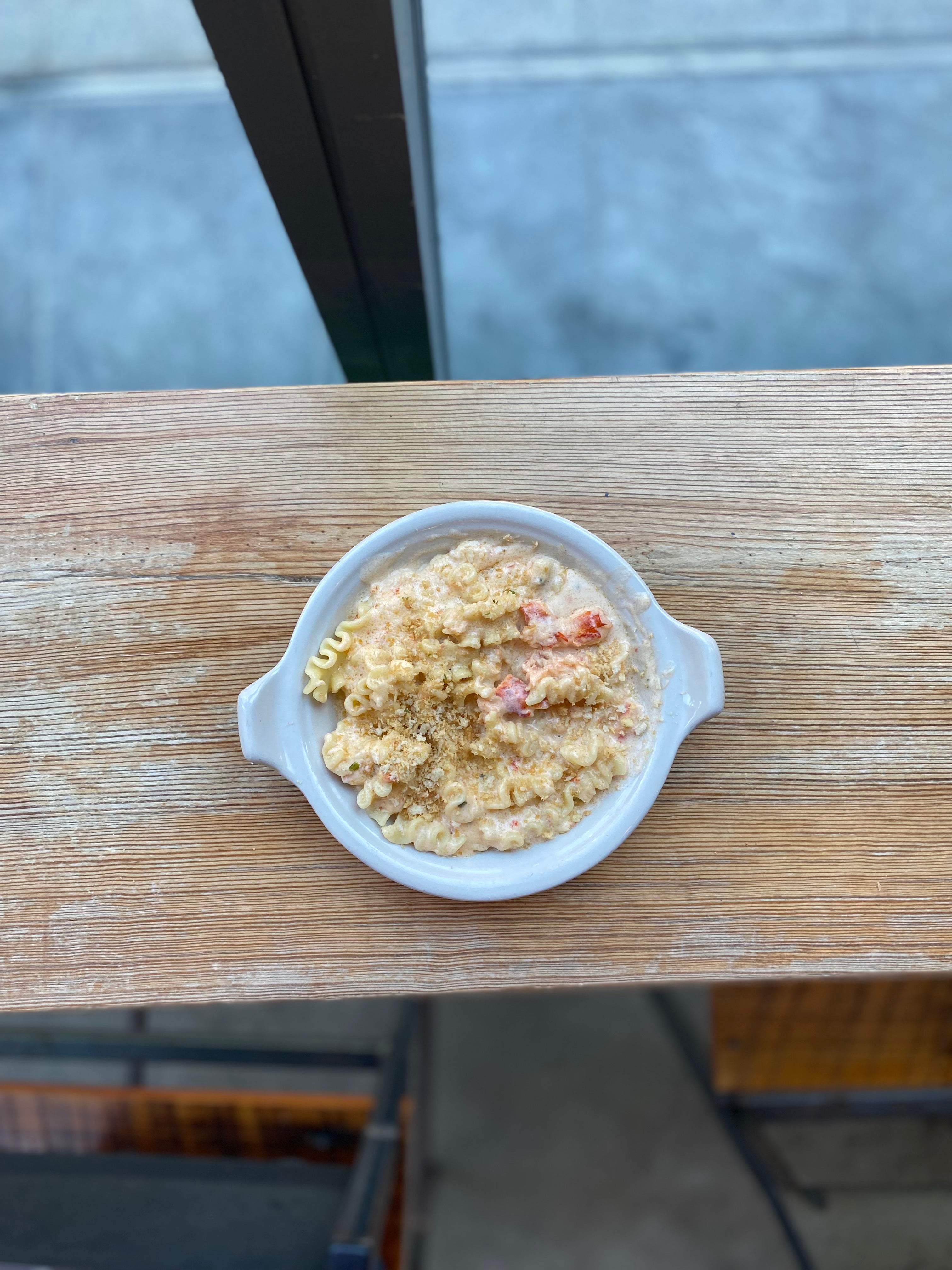 Lobster mac and cheese in a dish on a wooden table. 