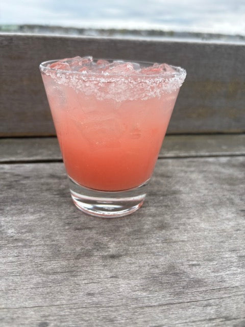 a margarita with a salted rim on the deck in front of the ocean