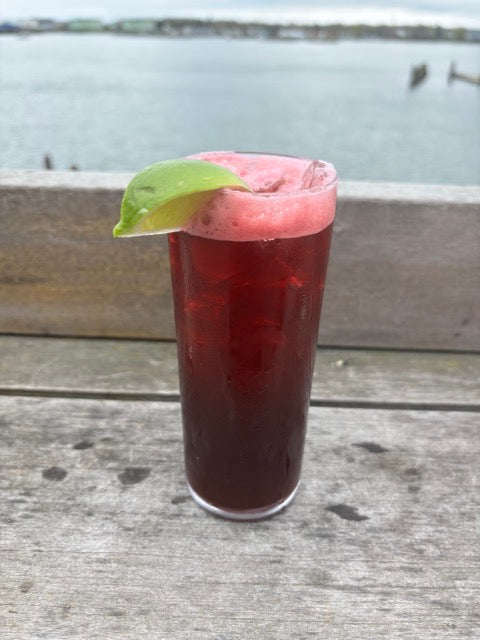 a blueberry mojito cocktail on a deck in front of the ocean