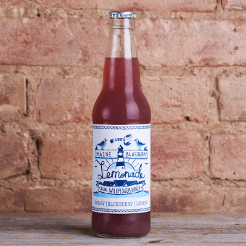 Luke's blueberry lemonade in a bottle in front of a brick wall