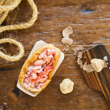 Luke's Truffle Butter Lobster Roll and white truffles next to rope on a wooden table