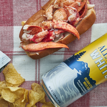 Lobster Roll and a can of Allagash White on a red and white tablecloth