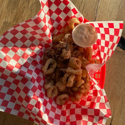 Fried golden calamari and tartar sauce in a basket lines with red and white wax paper