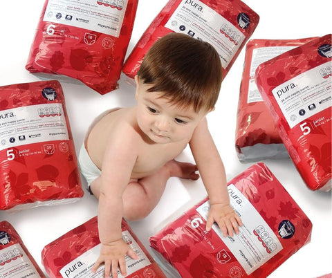 Baby surrounded by nappy pant packs
