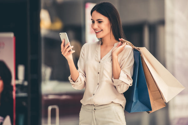 A woman holding shopping bags and looking at her phone