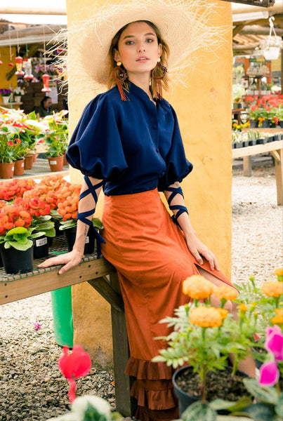 A woman wearing a beautiful fall-inspired orange skirt with deep blue Azulejo Blouse from Equal Hands 