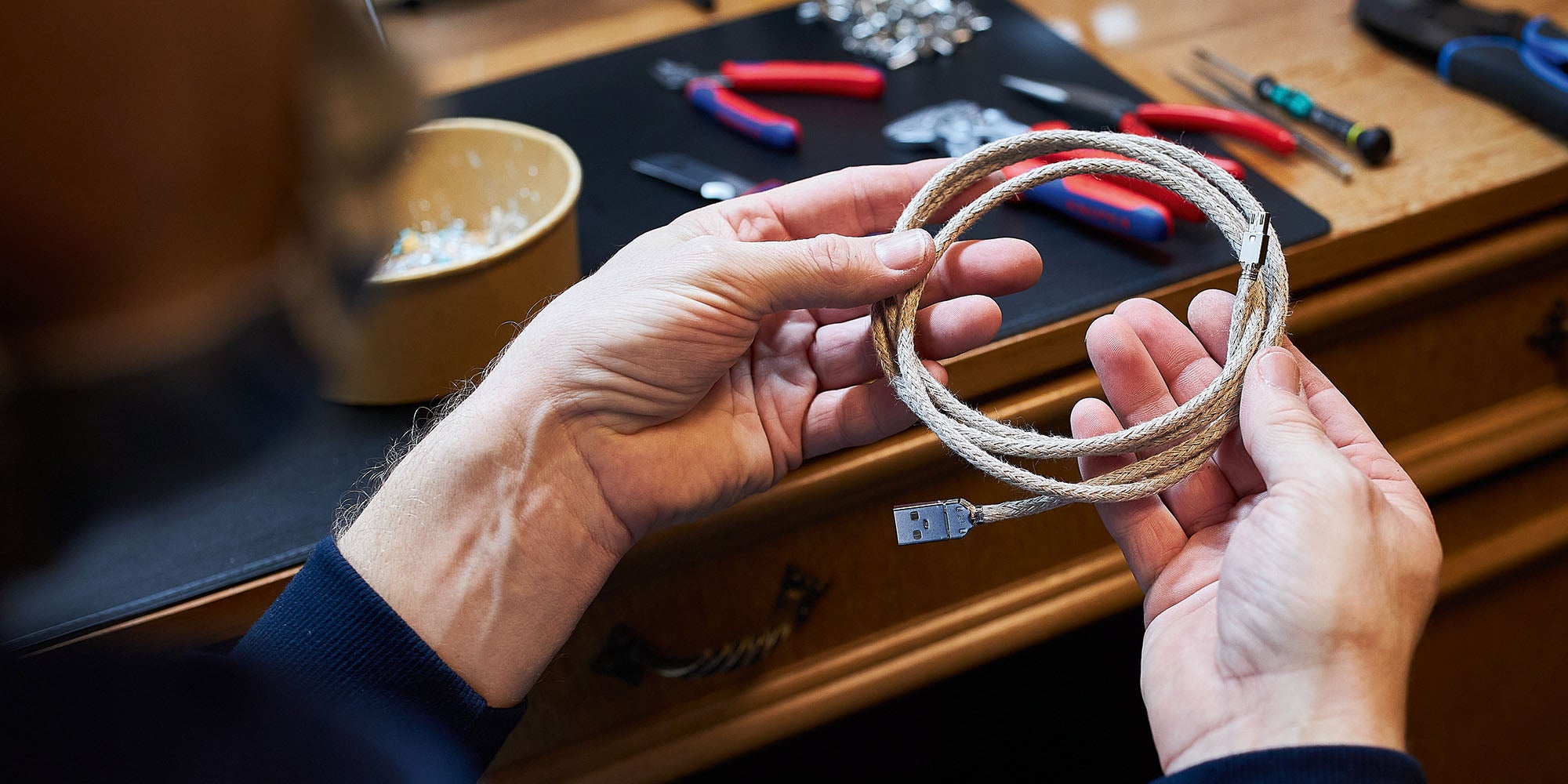 Cable builder Rene holds flax-sheathed USB-A to MicroUSB recable in raw form without heat shrink tubing.