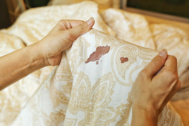 hands hold bed sheet with blood