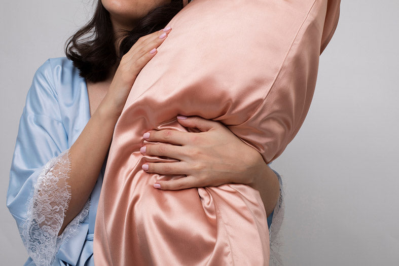 woman in silk pajama holding a pillow