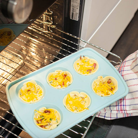 Découpez 24 petits cercles dans la pâte feuilletée. Graissez une plaque à mini-muffins et déposez les ronds de pâte dans les moules. Déposez le mélange à base de lardons sur les fonds, puis versez le mélange à base d'œufs. Parsemez du cheddar restant. Enfournez les quiches pendant 15 minutes avant de vous régaler.