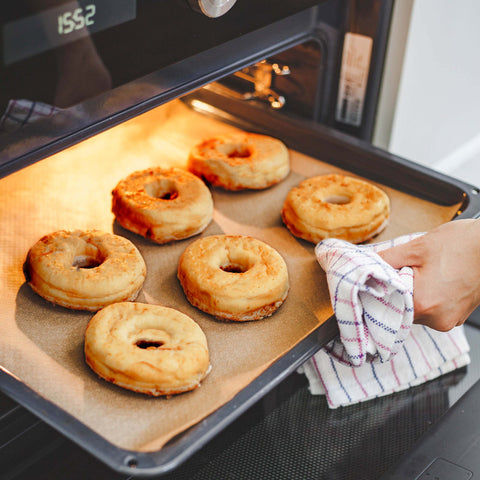 Bestuif je handen met wat bloem en verdeel het deeg in 8 donuts. Maak met een klein rond vormpje een gat in het midden. Bak de donuts vervolgens 20 minuten in een voorverwarmde oven van 190°C.