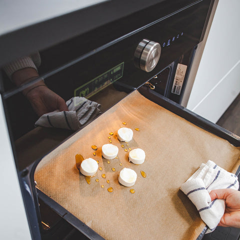 Besprenkel de geitenkaasjes met honing en bak ze 8 minuutjes op een bakpapier in een oven op 190 graden Celsius.