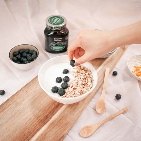 Doe de yoghurt, muesli en blauwe bessen in je bowl.