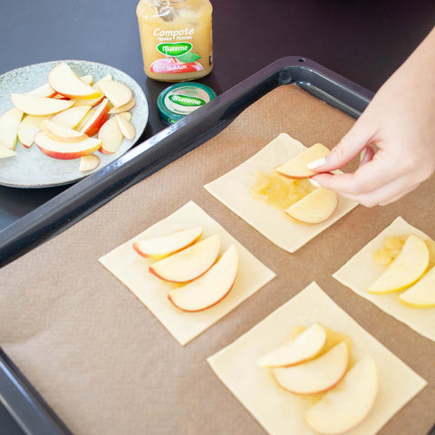 Déposez une couche de compote sur la pâte feuilletée, puis répartissez les tranches de pomme. Saupoudrez de sucre. 