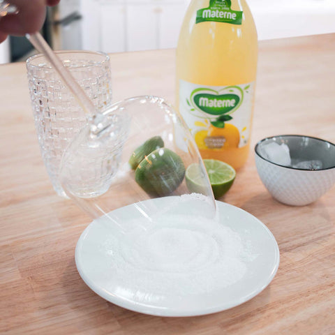 Pressez le ½ citron vert. Avec l’autre moitié, frottez le bord de votre verre. Retournez-le, puis recouvrez le bord de sucre. Laissez sécher.