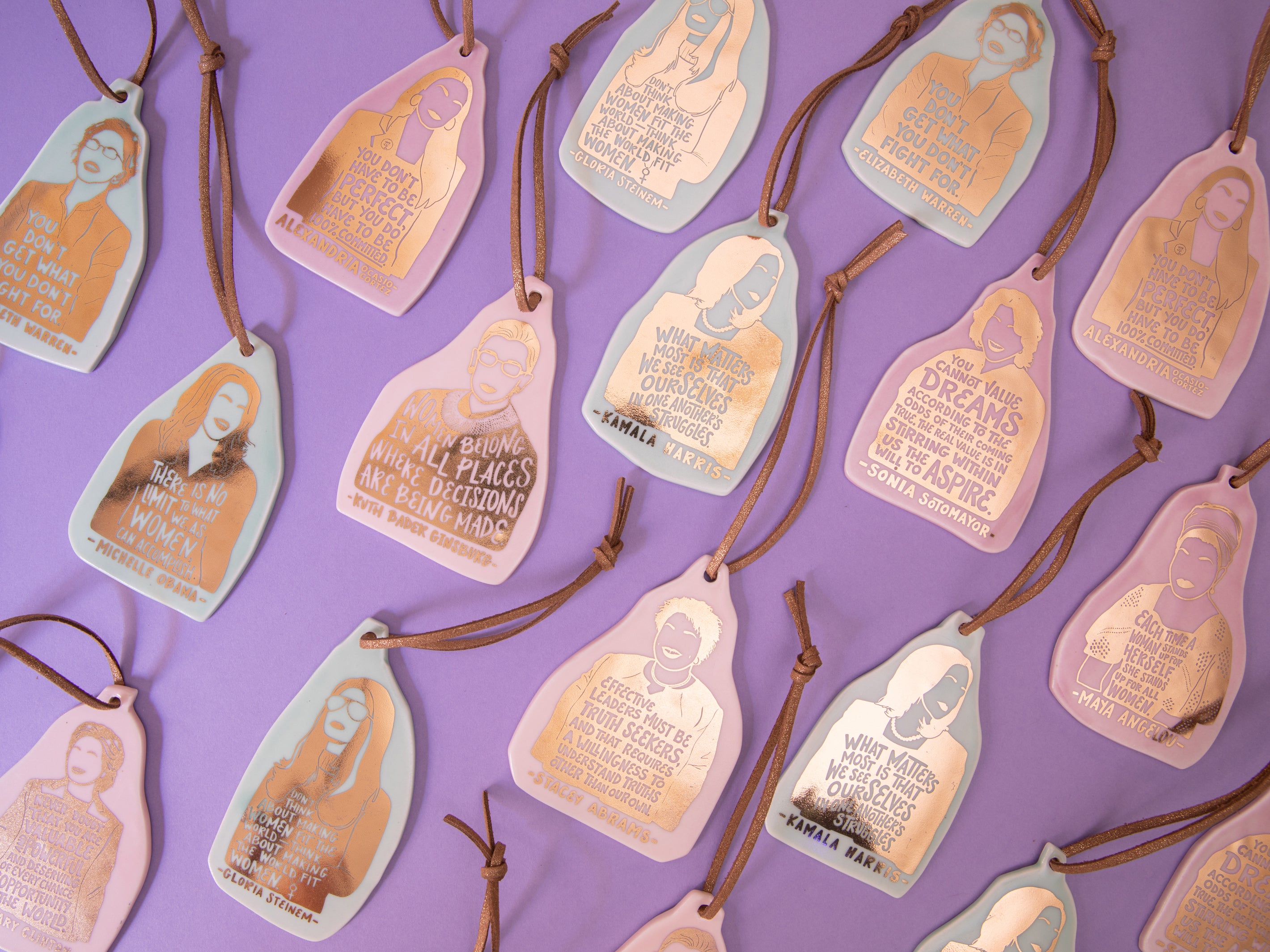 Assortment of feminist ceramic ornaments with gold foil by ARCHd and Christina Kosinski on purple background