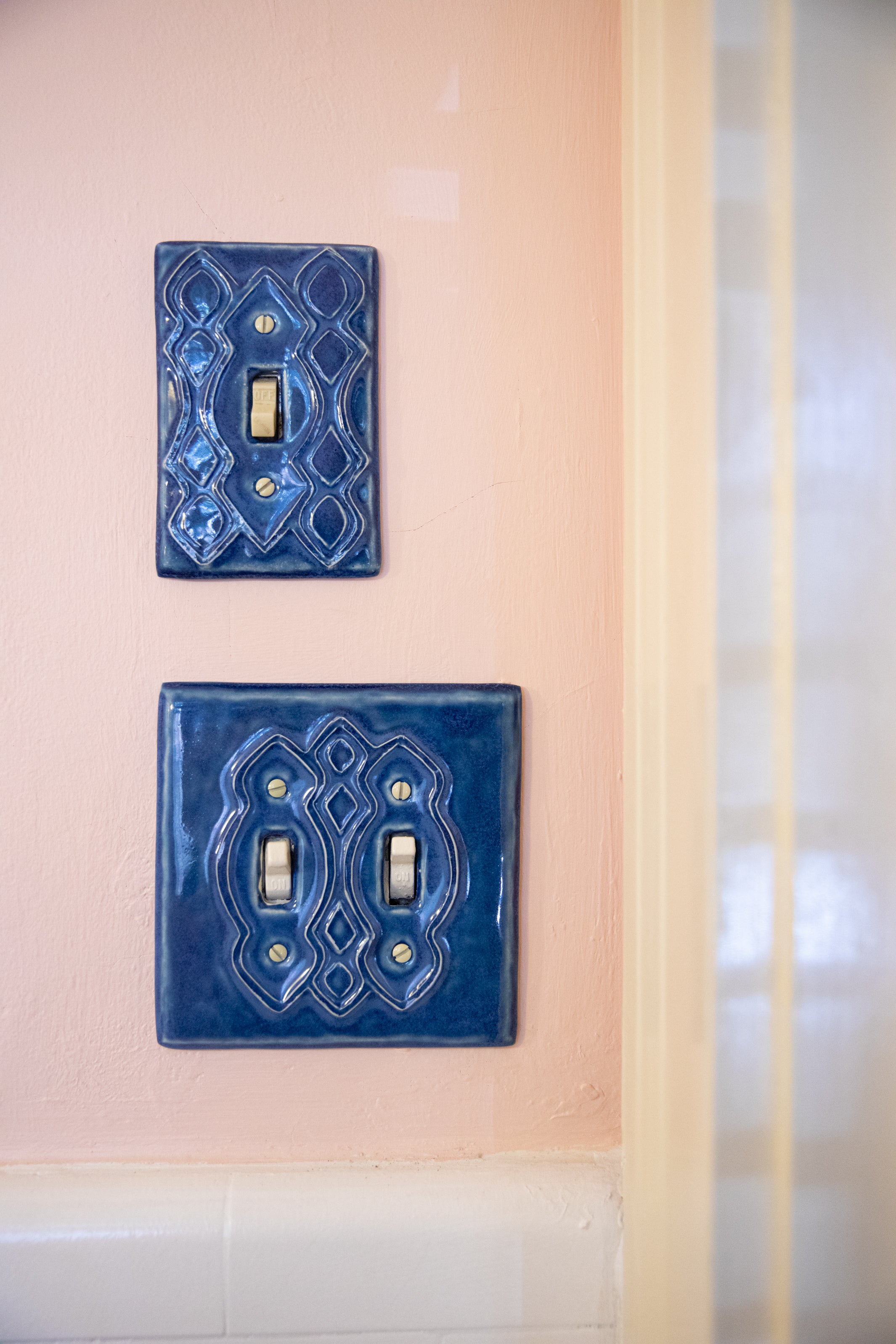 Moroccan Light Switch Plate in Sapphire Blue Gloss Glaze on light pink wall by Honeybee Ceramics