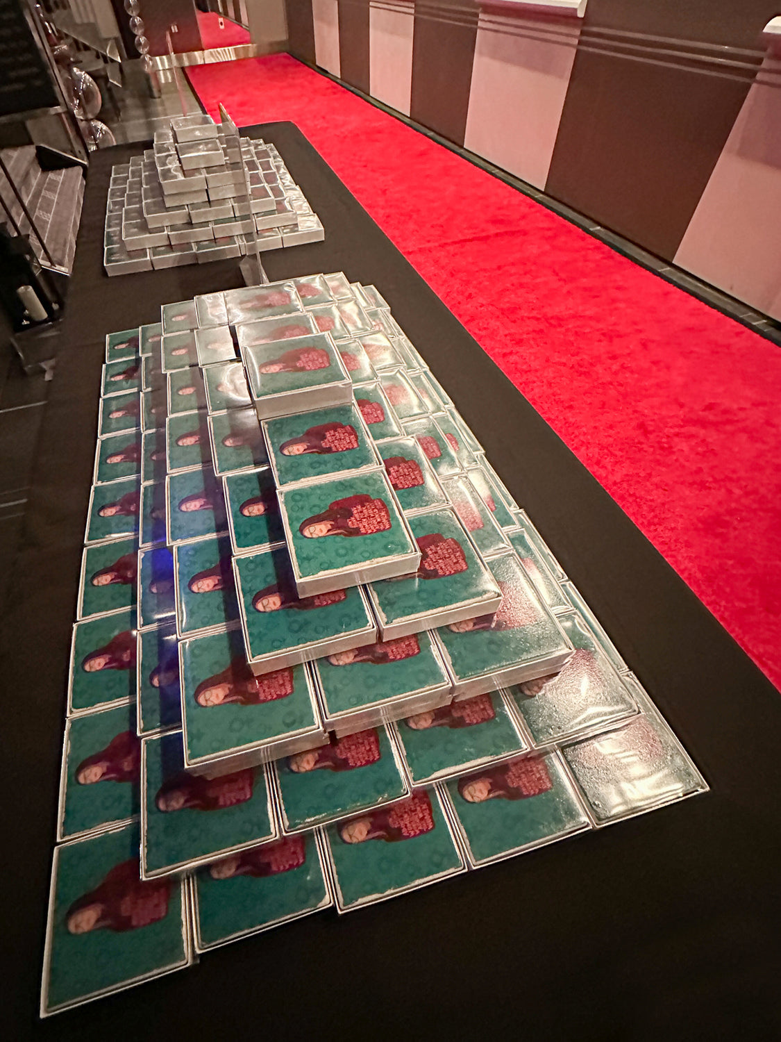long black table with gloria steinem coasters on it beside a red carpet