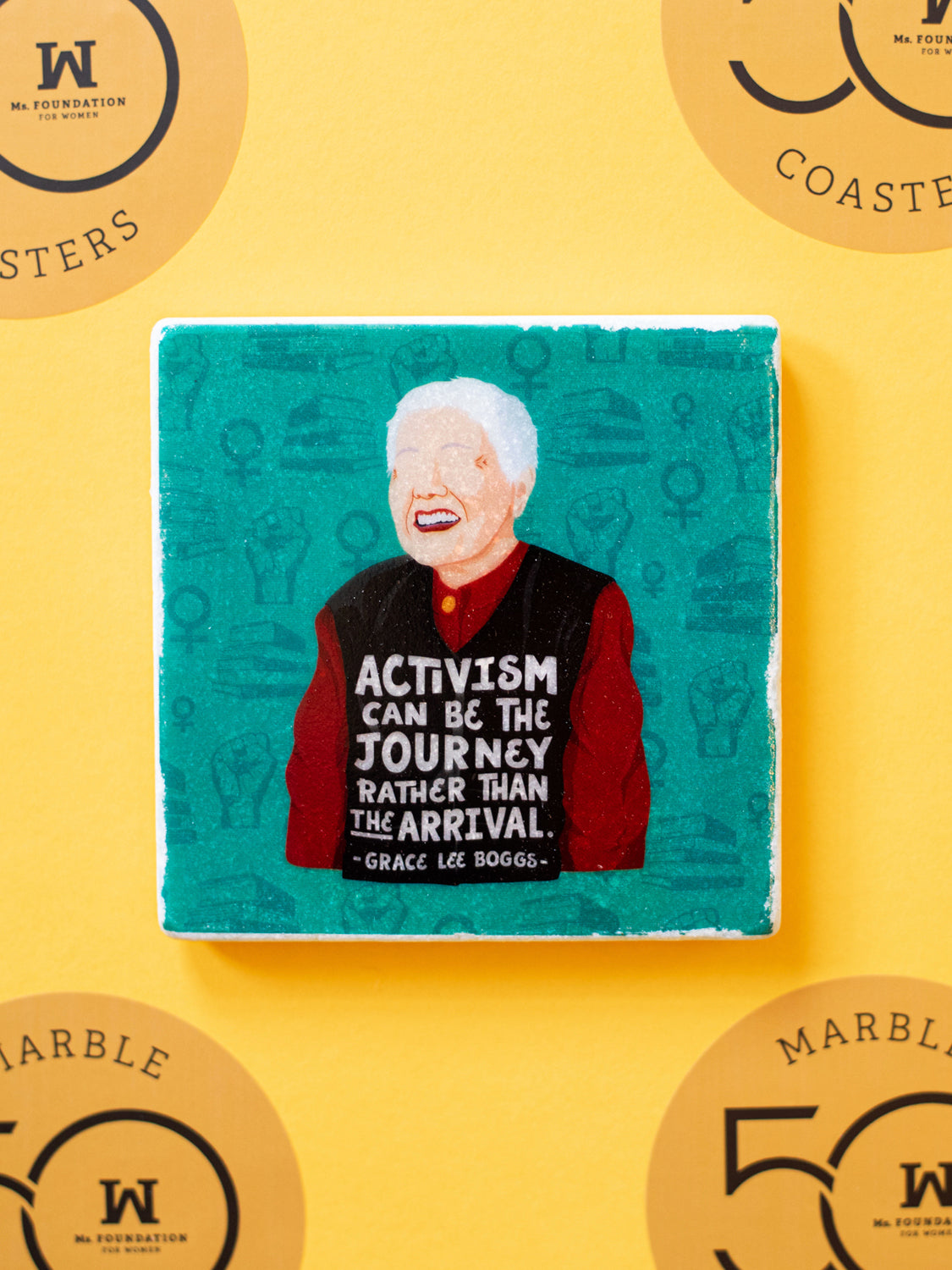 Marble coaster with illustration of chinese american activist grace lee boggs with the quote, "Activism can be the journey rather than the arrival." on a gold background