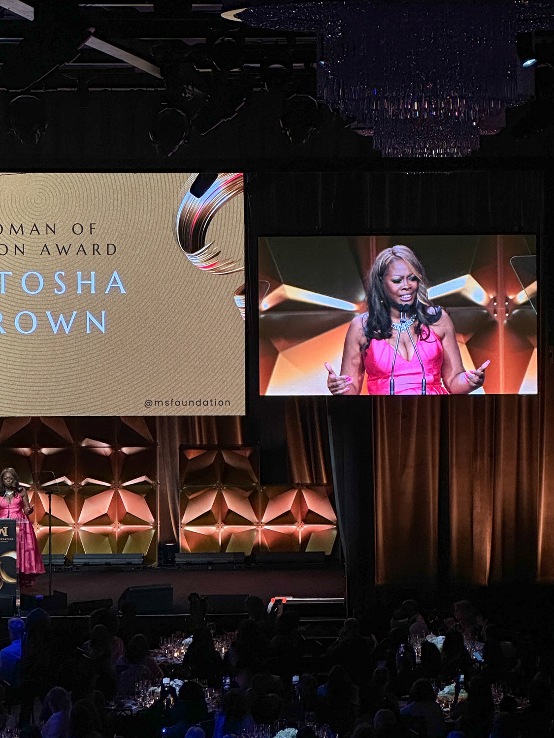 latosha brown, woman in pink dress speaking on stage at gala event