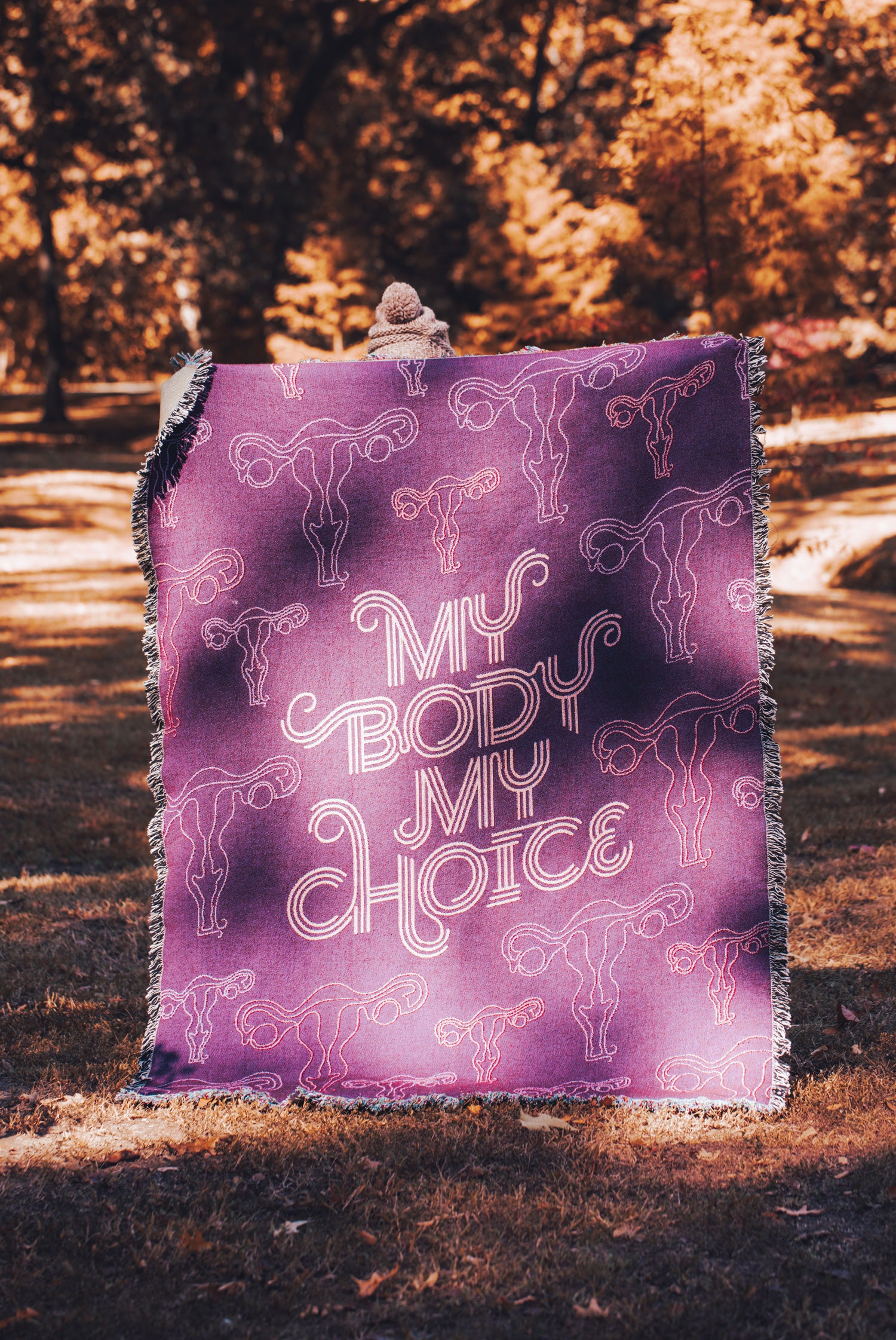 My Body My Choice surrounded by pattern of uterus Illustrations, all on dark purple woven blanket with fringe