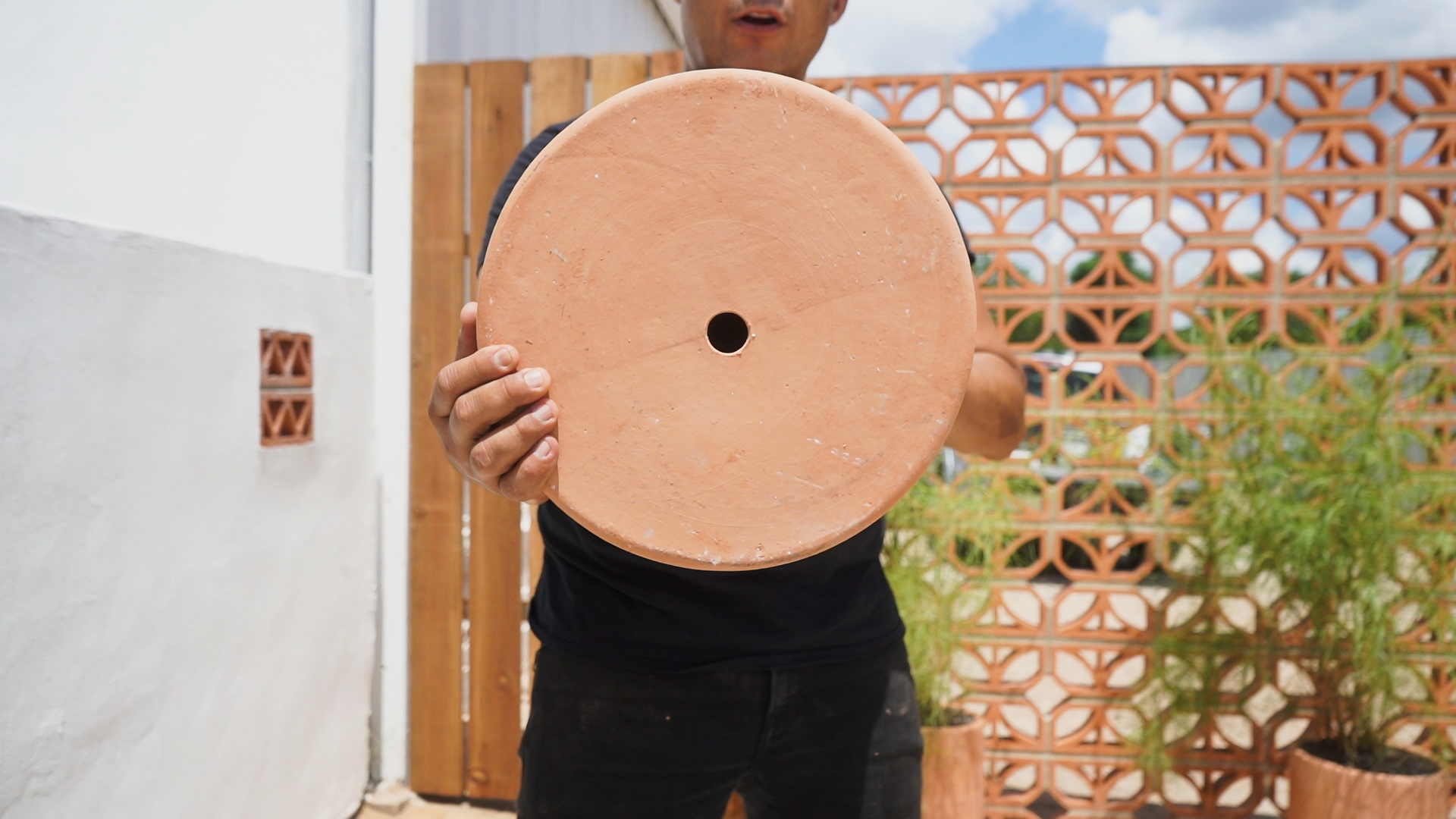 Man holding bottom of clay planter clay imports