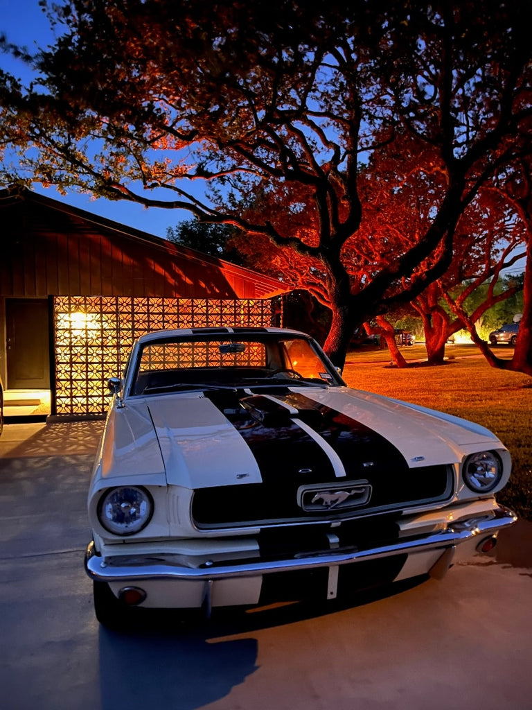 A car outside a house with a terracotta breezeblocks wall at night