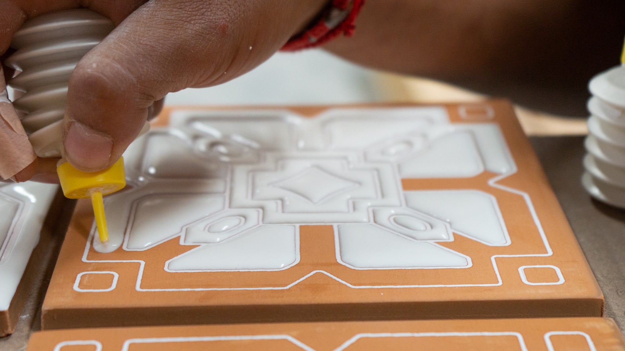 Relief tile being painted with white paint by hand clay imports