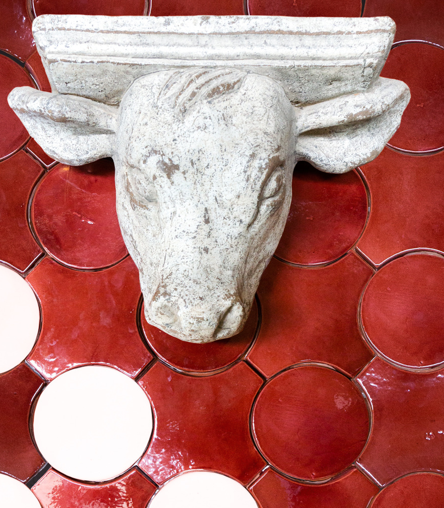 Red and white round tile with bull head statue from paseo series kim wolfe clay imports