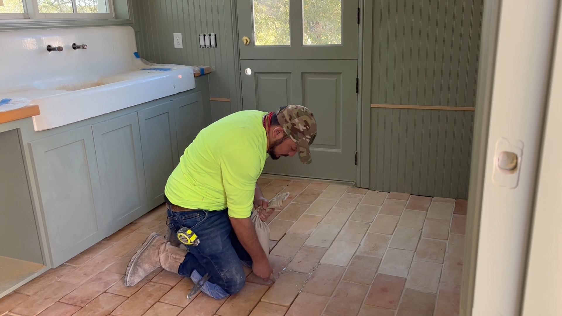 Tile installer grouting clay pavers into floor at @FinnFamilyFarm